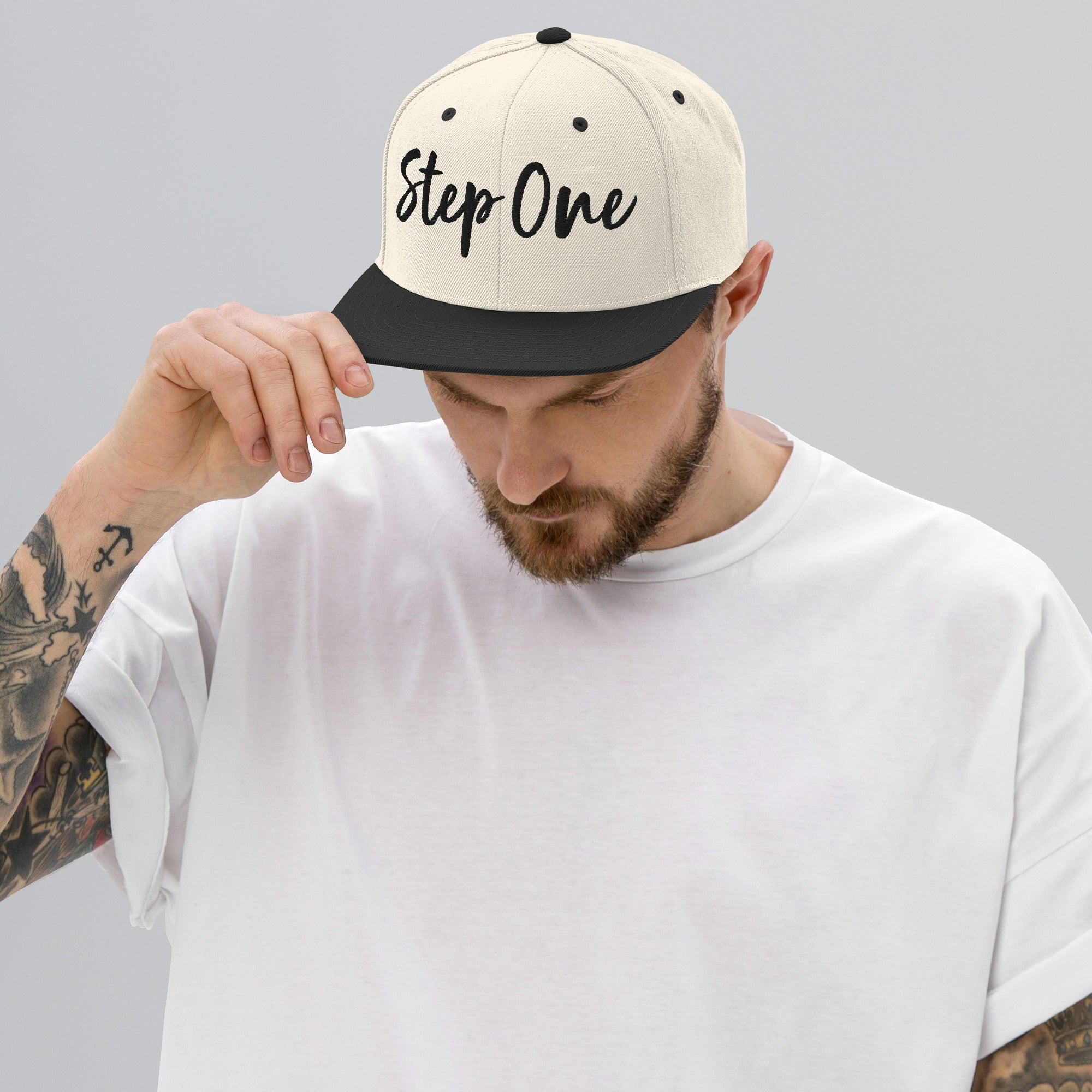 A man wearing a white snapback hat with the text 'Step One' embroidered on the front.