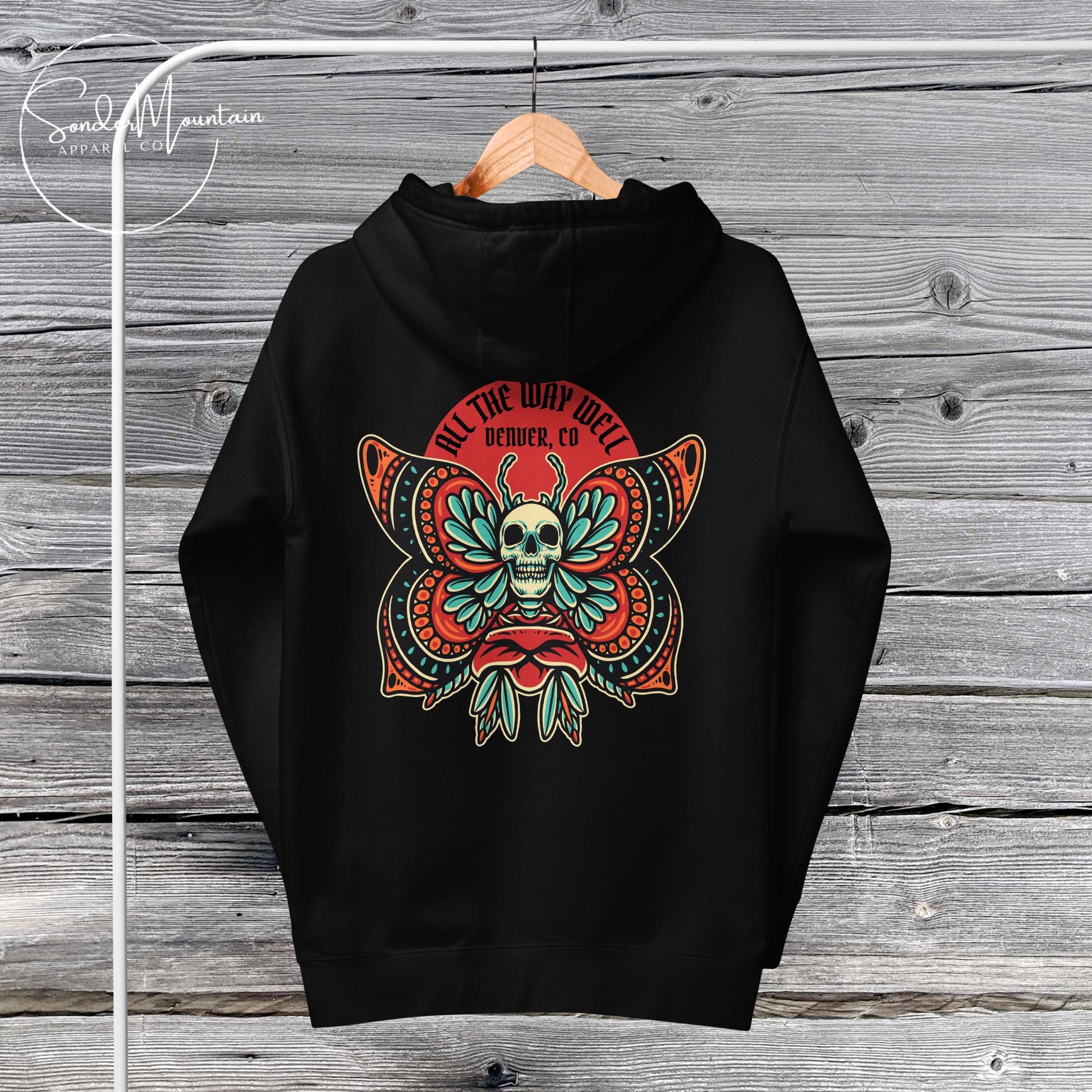 A black unisex hoodie with a graphic design featuring a skull, plants, and text on the front.