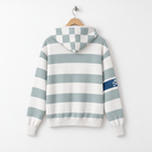 A hooded sweatshirt shown from the back, hanging on a wooden hanger against a plain white wall. The hoodie has horizontal stripes in a muted blue-gray and off-white, with a matching checkerboard pattern on the hood and a small dark blue sleeve patch featuring a white graphic.