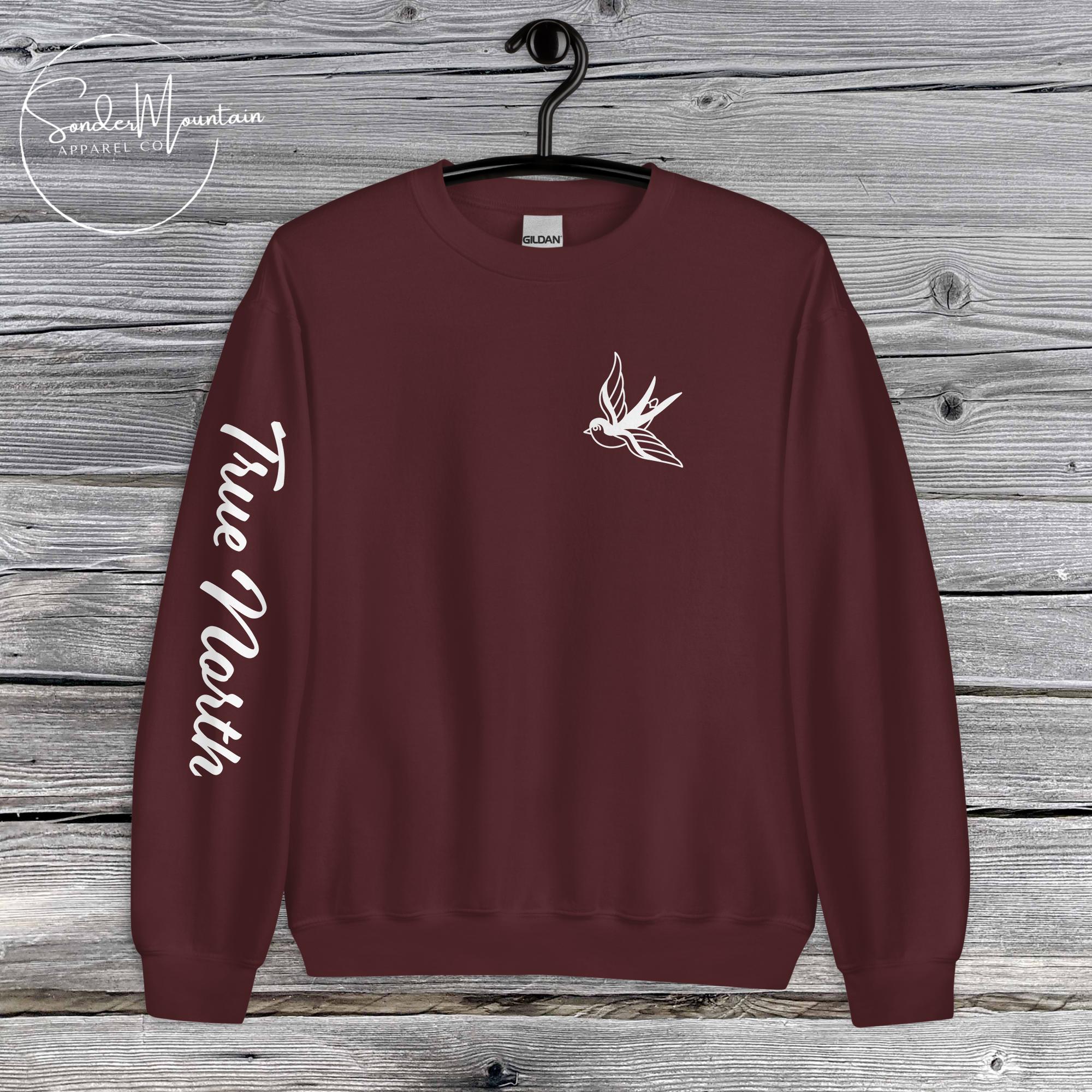 True North Mountain Classic tattoo-inspired unisex sweatshirt with 50% cotton and 50% polyester blend, pre-shrunk classic fit, air-jet spun soft low-pill fabric, 1x1 athletic rib-knit collar with spandex, double-needle stitched collar, shoulders, armholes, cuffs, and hem, bold sleeve typography and ink-inspired graphics, mission-driven streetwear designed for comfort, durability, and purposeful expression.